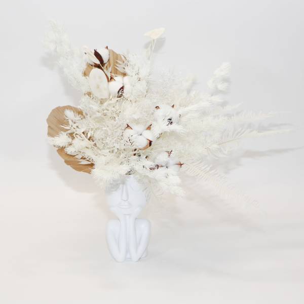 White floral arrangement in a white face-shaped vase