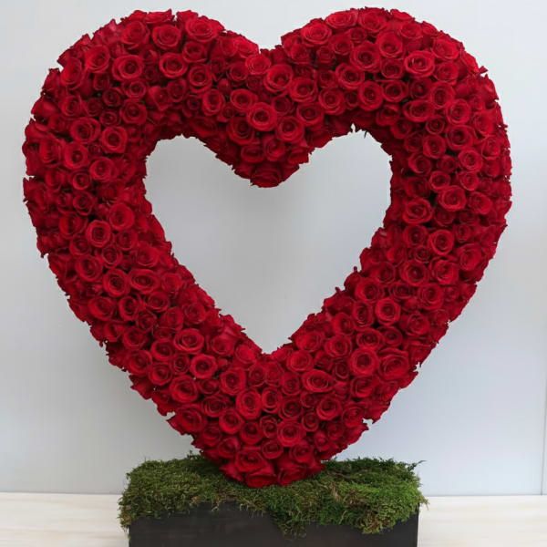 Large open heart of red roses on a moss-covered rectangular base