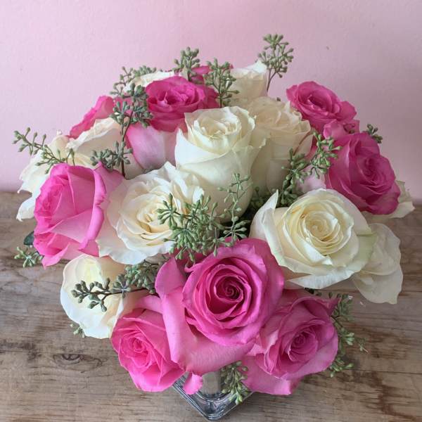 Pink and white roses arranged in a clear glass vase