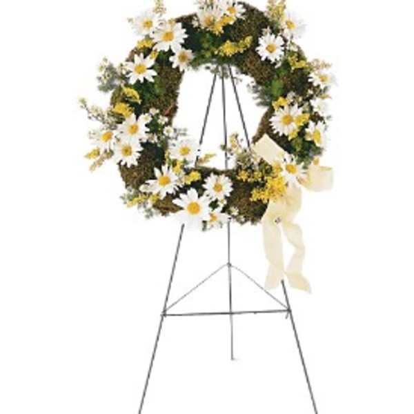 Standing wreath with white daisies, yellow accents, and cream ribbon on a metal easel