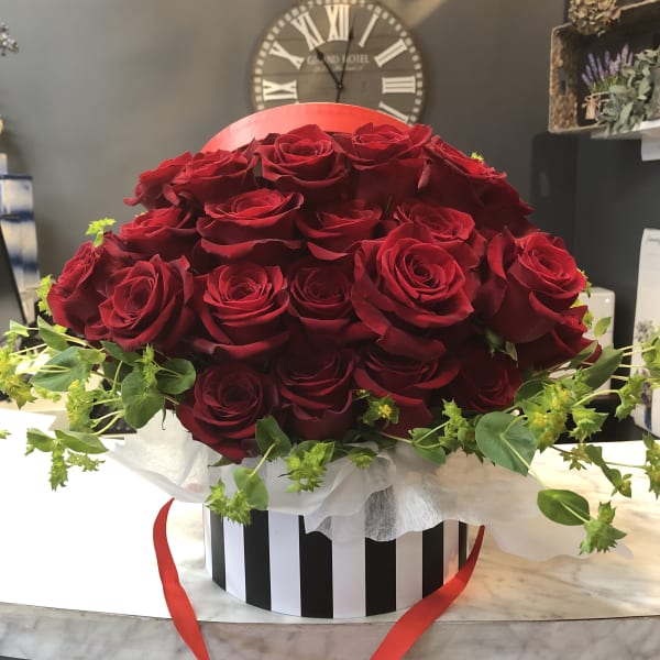 Large bouquet of red roses in a striped hatbox with a red ribbon