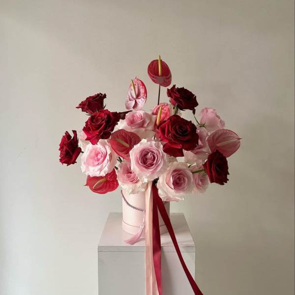 Bouquet of pink and red roses with anthuriums in a pale box