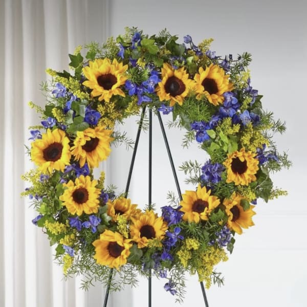 Sunflower wreath with blue flowers on a black stand