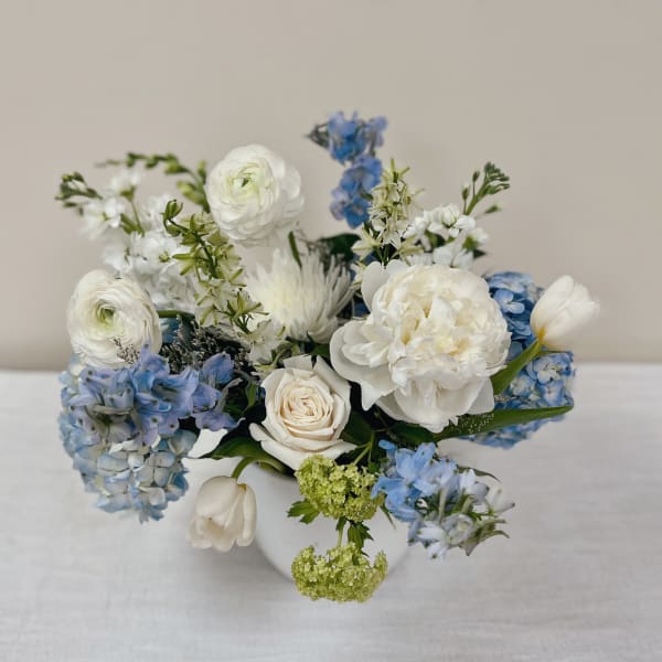 White and blue mixed flower arrangement in a white vase
