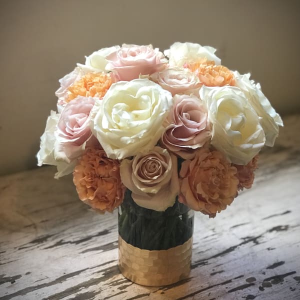 Bouquet of pale pink, white, and peach roses in a gold vase