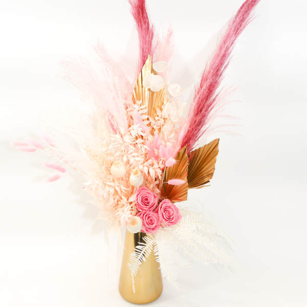 Pink roses and dried pampas-style stems in a gold vase