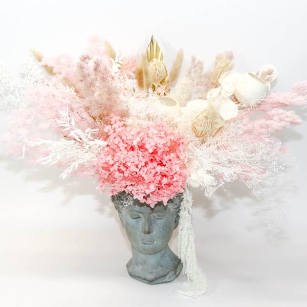 Pink and white dried floral arrangement in a sculpted face vase