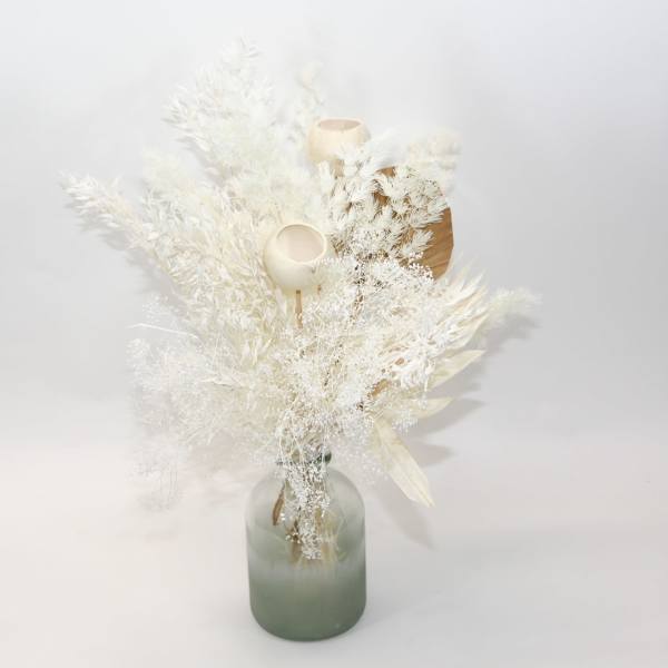 White dried floral arrangement in a frosted glass vase