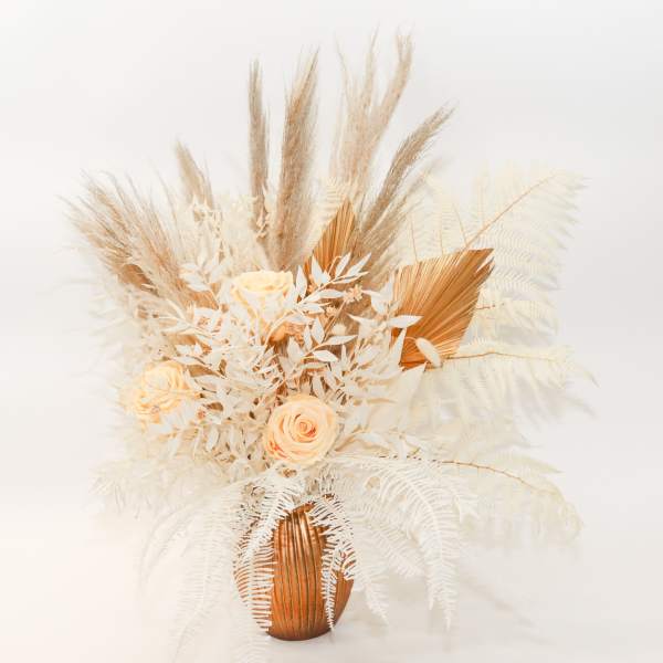 Cream roses in a copper vase with dried pampas grass and white fern-like foliage