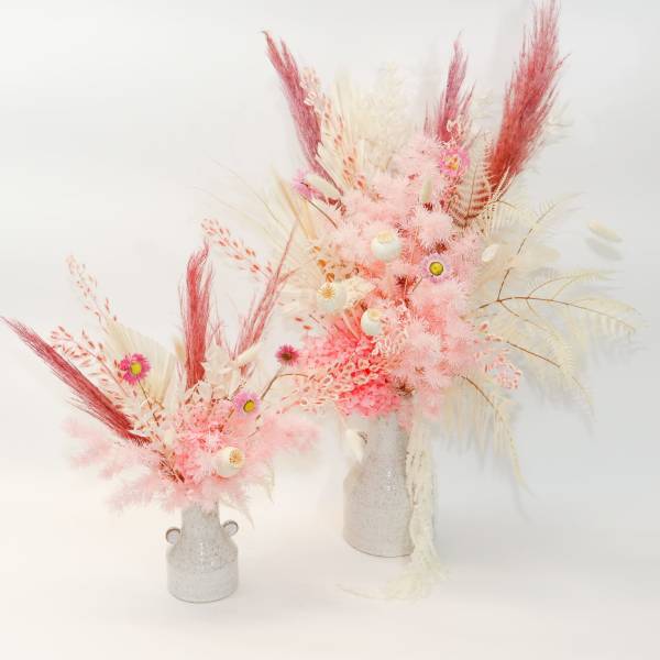 Two pink and white dried floral arrangements in small vases