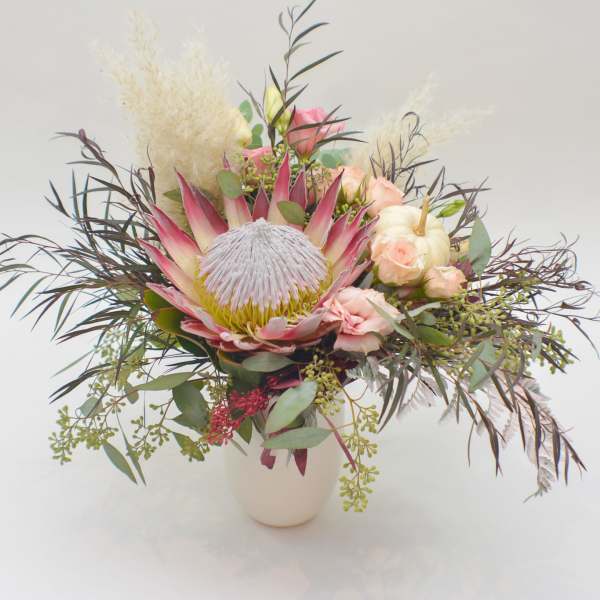 Mixed bouquet with a large pink protea in a white vase