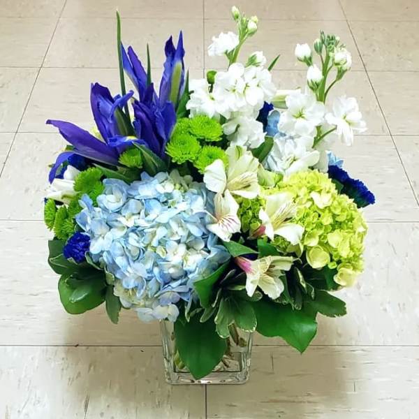 Blue and white floral arrangement in a clear square vase