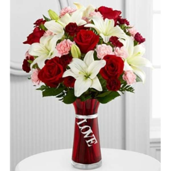 Bouquet of red roses, white lilies, and pink carnations in a red vase