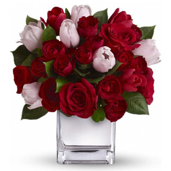 Red and pale pink roses arranged in a clear square vase