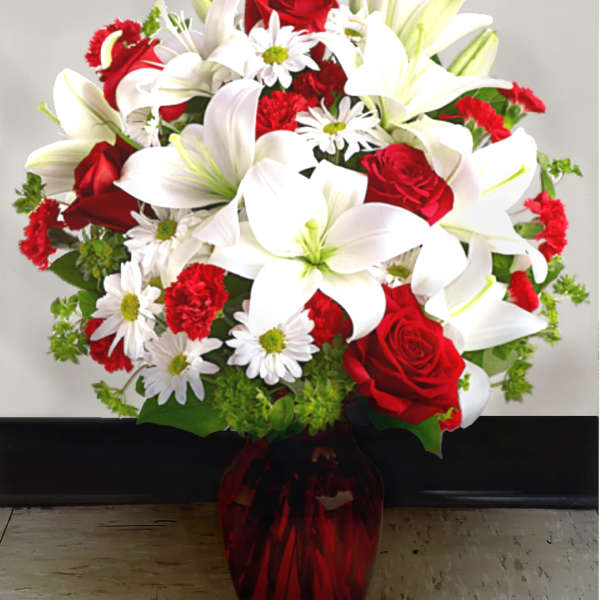 Bouquet of red roses, white lilies, and white daisies in a red vase