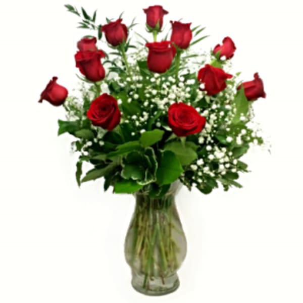 Red roses arranged in a clear glass vase with baby's breath