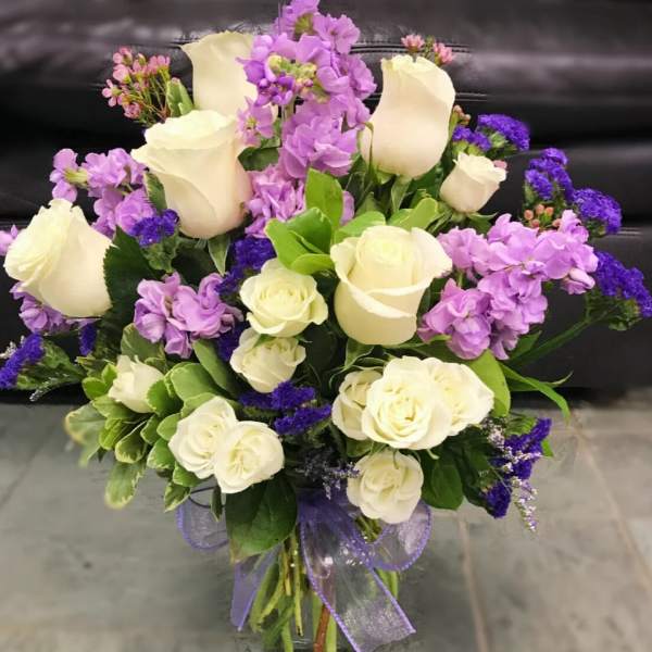 Bouquet of white roses and purple flowers in a glass vase