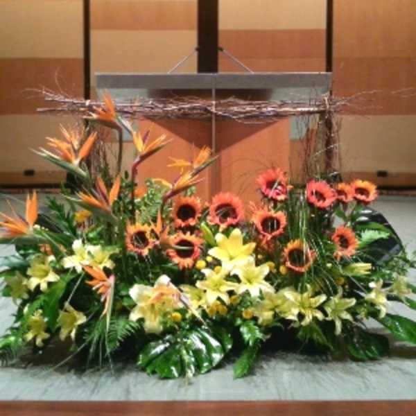 Large orange and yellow tropical flower arrangement displayed in front of a podium
