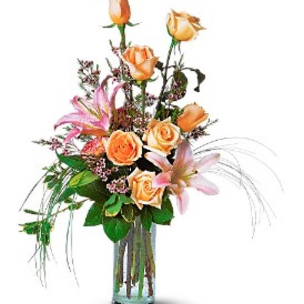 Orange roses and pink lilies in a clear glass vase
