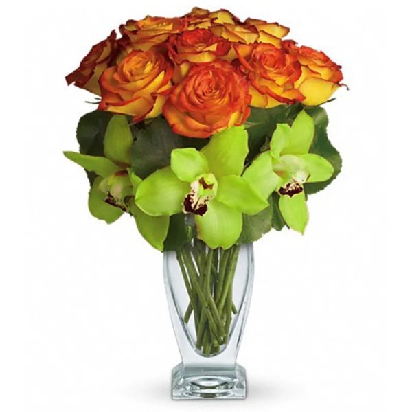 Bouquet of orange and yellow roses with green orchids in a clear glass vase