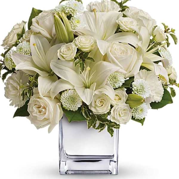 White lilies and roses arranged in a clear glass vase