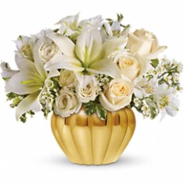 Short arrangement of white lilies and cream roses in a round gold vase