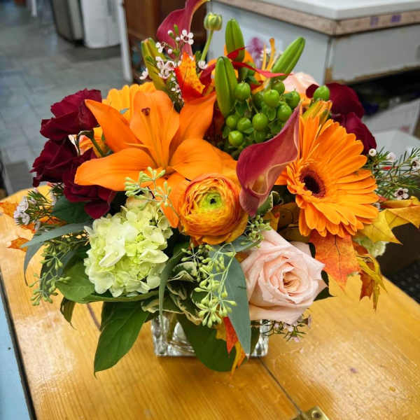 Mixed bouquet with orange lilies, gerbera daisies, and roses in a glass vase