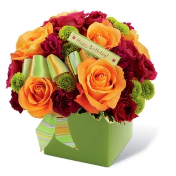 Bouquet of orange and red roses in a green gift box with a birthday tag