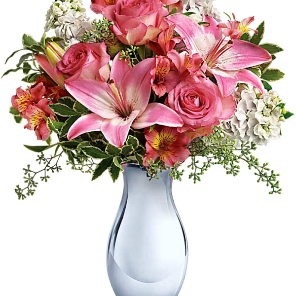 Pink roses and lilies arranged in a blue glass vase