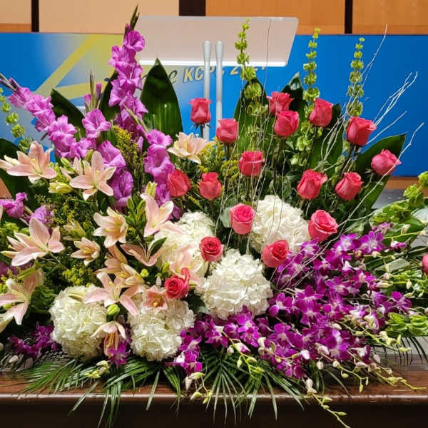 Large altar-style arrangement with pink roses, lilies, orchids and white hydrangeas