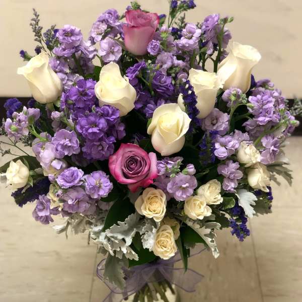 Bouquet of pink and cream roses with purple flowers in a glass vase