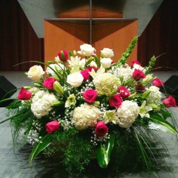 Large altar-style arrangement of red and white flowers with lilies and hydrangeas.
