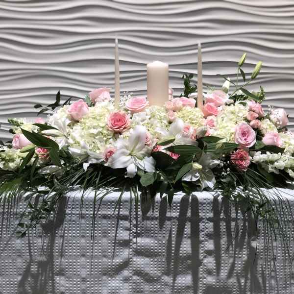 Pink and white floral centerpiece with candles on a table