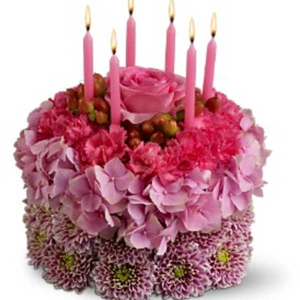 Pink floral cake with lit pink candles on top