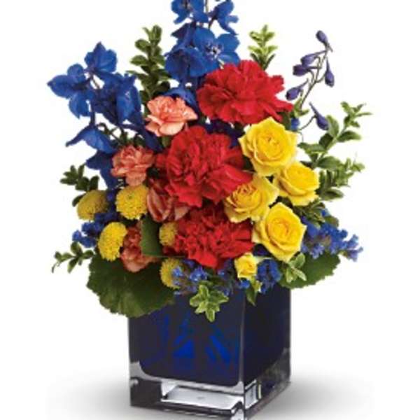 Colorful bouquet of red, yellow, blue, and peach flowers in a square vase