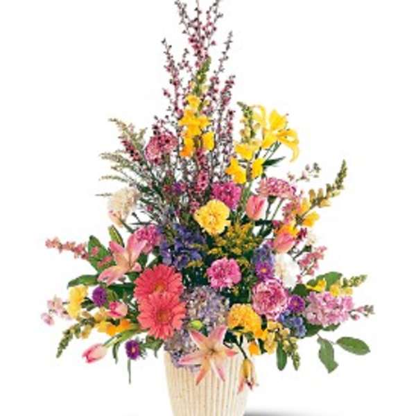 Tall mixed arrangement of pink, yellow, and purple flowers in a cream pot