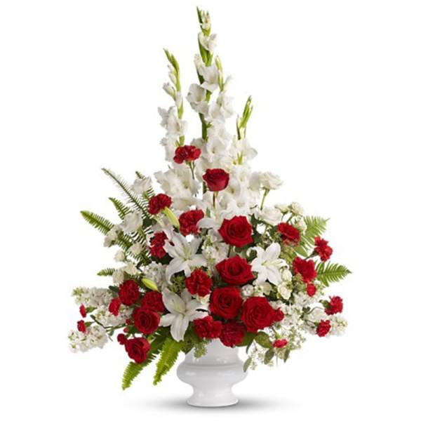 Tall red and white floral arrangement with roses, carnations, and lilies in a white urn vase