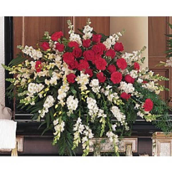 Large spray of red roses and carnations with white flowers arranged on a casket