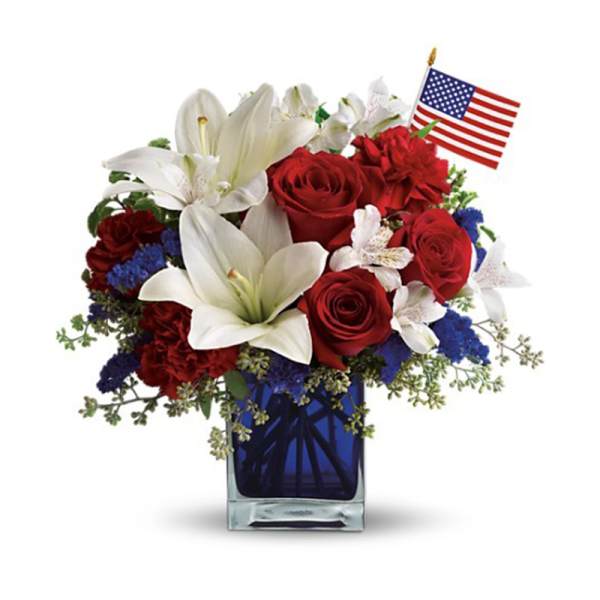 Red roses and white lilies in a blue vase with a small American flag