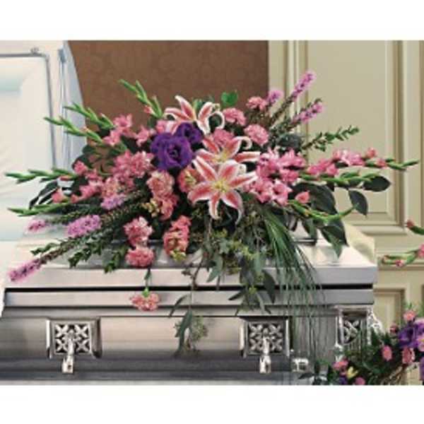 Pink and purple casket spray with lilies and carnations on a silver casket