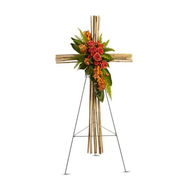 Tall bamboo cross on a metal stand accented with orange roses and other orange flowers.