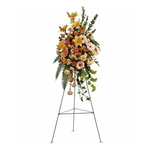 Tall standing spray of peach and orange lilies, roses, and daisies on a metal easel