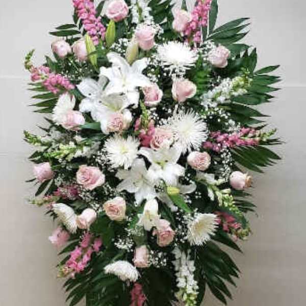 Tall standing spray of white lilies and mums with pink roses on a metal easel