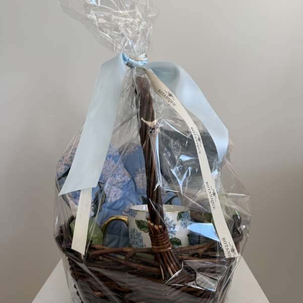 Gift basket with a blue mug and wrapped items in a wicker basket
