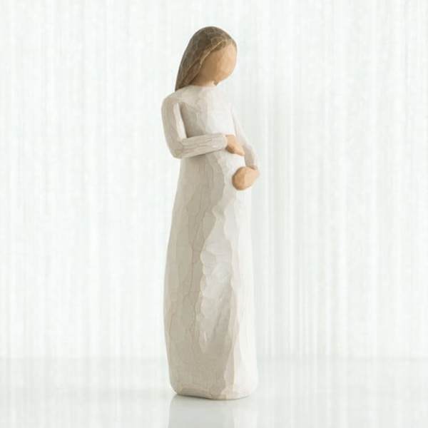 Wooden figurine of a pregnant woman in a white dress