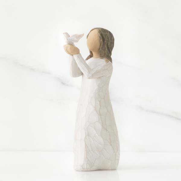 Small angel figurine in a white dress holding a dove