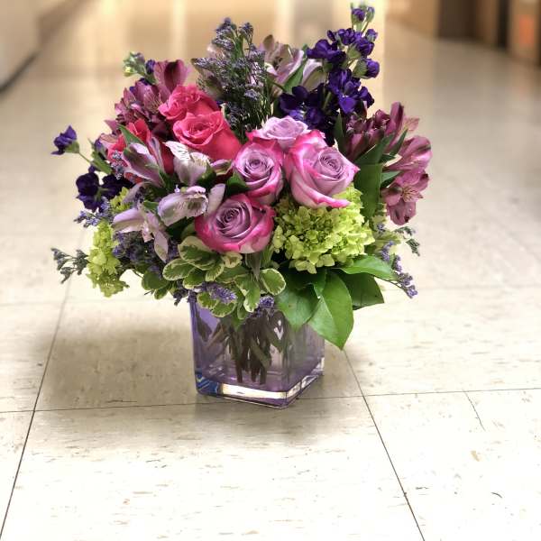 Pink and purple rose bouquet in a square glass vase