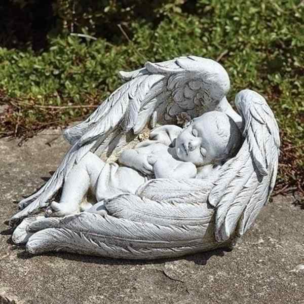White angel statue cradling a sleeping baby on a stone surface
