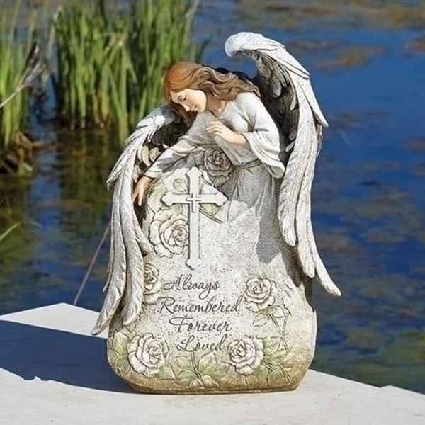 Angel memorial statue with a cross and floral engraving