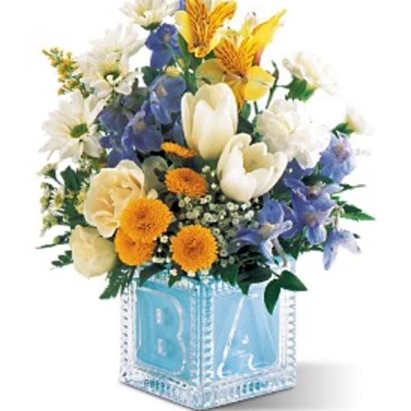 Mixed bouquet in a blue glass cube vase with white, yellow, and blue flowers